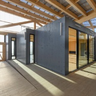 Room-sized timber modules define spatial units in a timber hall.