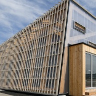 Side view of the Switzerland Innovation Park in Dübendorf with view of the covering structure comprising wooden slats and a membrane.