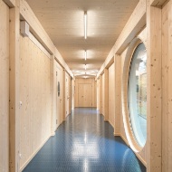 Gang mit Holzwänden und -decke in der Sporthalle.