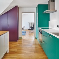 Einbauküche mit farbigen Schrankfronten sowie Fussboden aus Holz