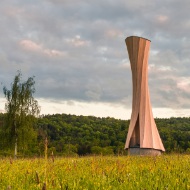 The photograph shows the entire Urbach Tower amid a flower meadow in the evening sun