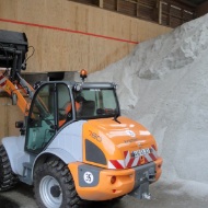 A front loader feeds a module conveyor system with salt