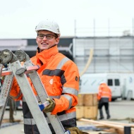 Assembly worker with a ladder during the assembly of a round timber silo