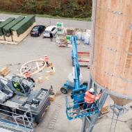 Montagemitarbeiter in Hebebühne bei Schraubarbeiten am Silo