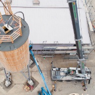 Round timber silo suspended from a crane, seen from above