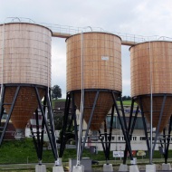 Drei runde Silos aus Holz nebeneinander platziert und mit Dachübergang miteinander verbunden, St.Gallen Neudorf