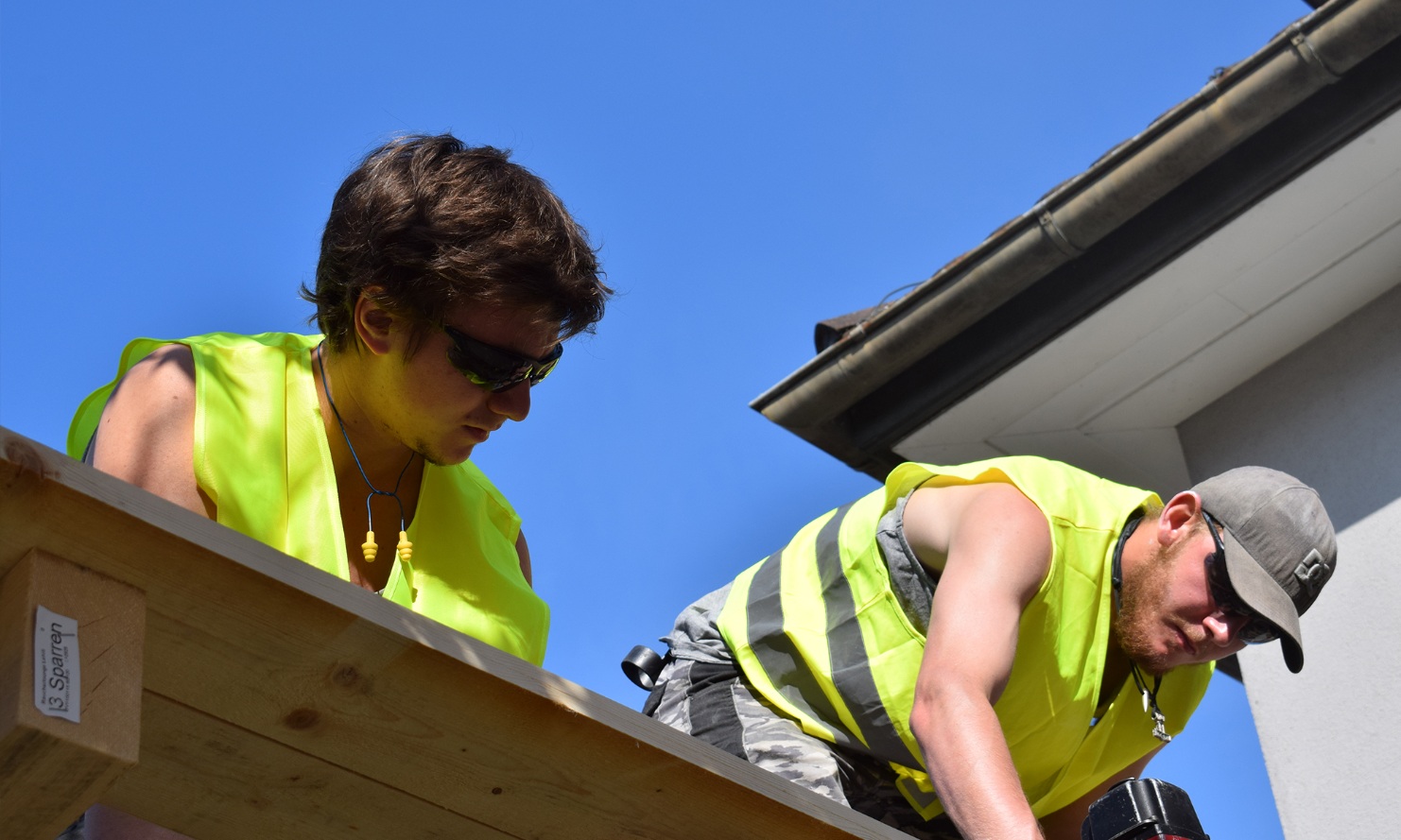 Zwei Lernende auf dem Dach am Arbeiten