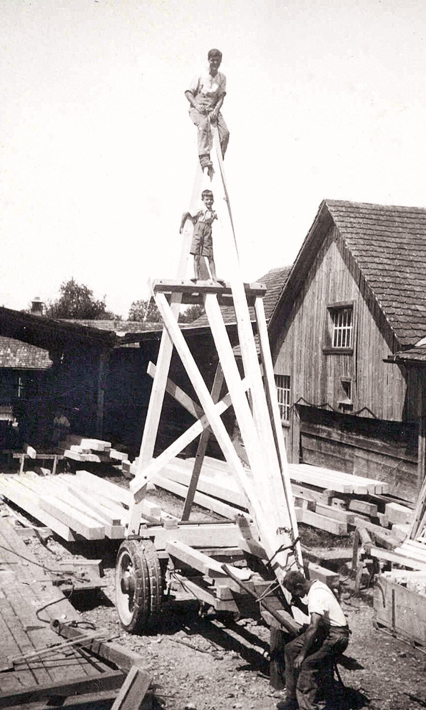 Photos of a very high timber framework with a worker and child at the top.