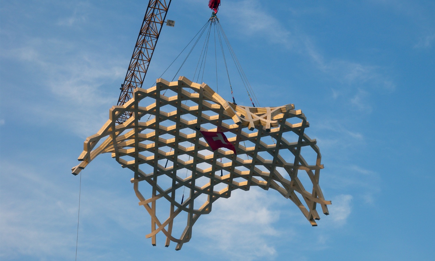 Photo d’une immense pièce de forme libre suspendue en hauteur sur la grue pour montage