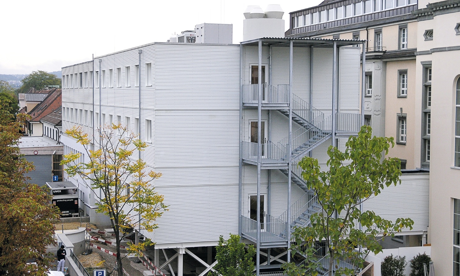 Overall view of the three-storey St. Clara temporary hospital building in a timber modular construction with stair entrance at the front of the building