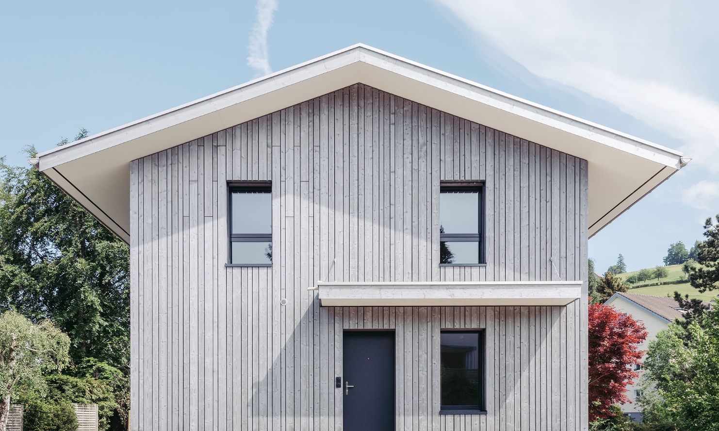 Exterior view of the detached house: an abundance of wood in different structures and colours.