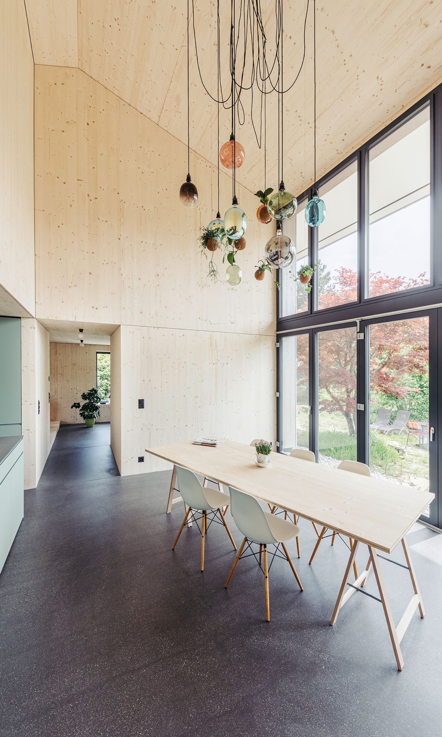 Blick ins Esszimmer mit langem Tisch und Stühlen vor der Fensterfront.