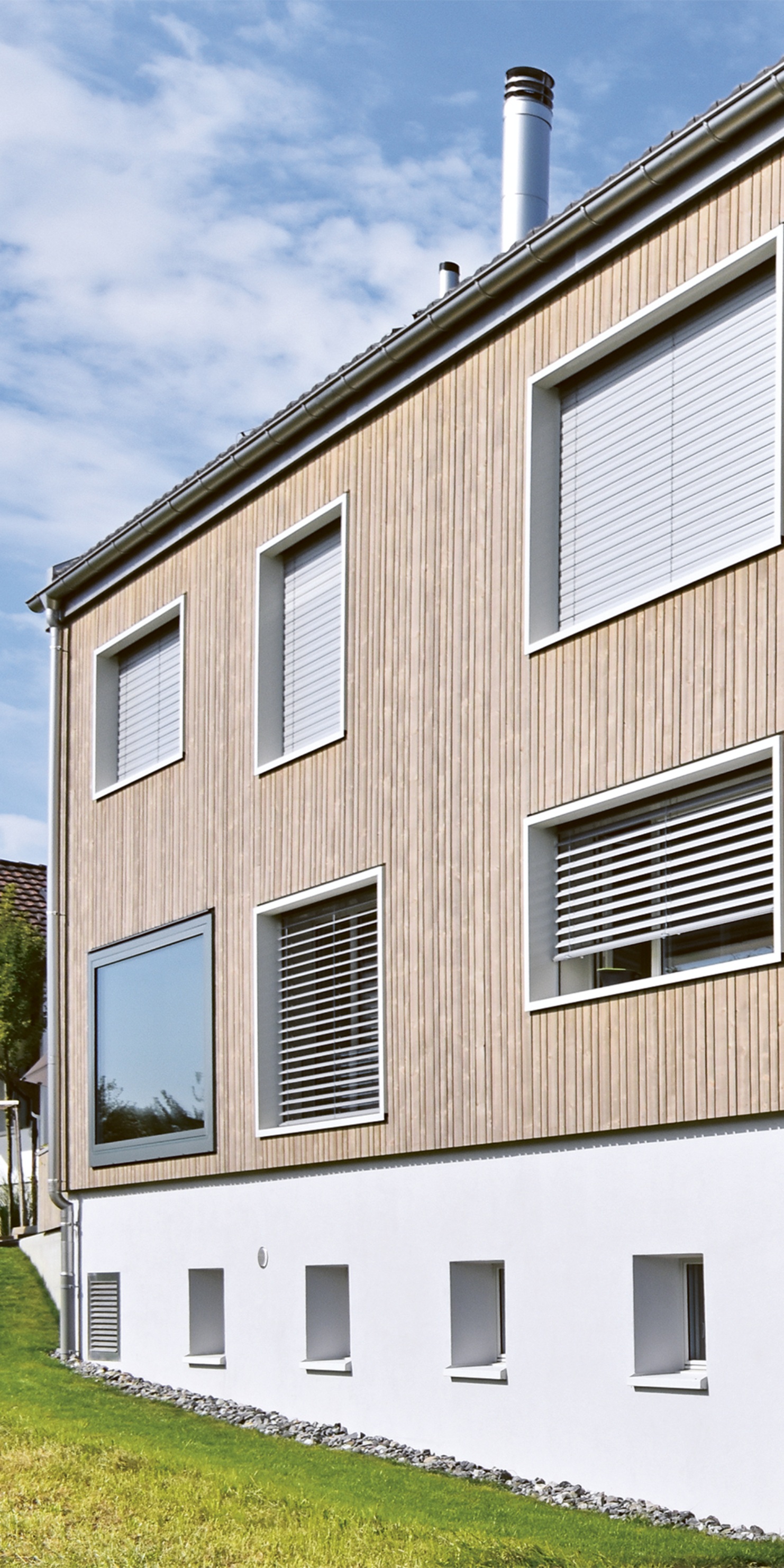 Vue de la façade d’une maison individuelle baignée de lumière sous un ciel bleu