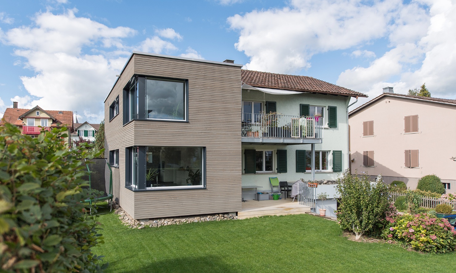 Vue générale de la maison individuelle avec extension moderne et jardin dans le quartier résidentiel.