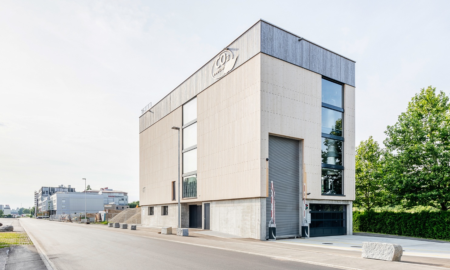 Gesamtansicht der viergeschossigen Energiezentrale mit vertikal verlegter Fassade mit sägeroher Sicht-Nut-Schalung. 