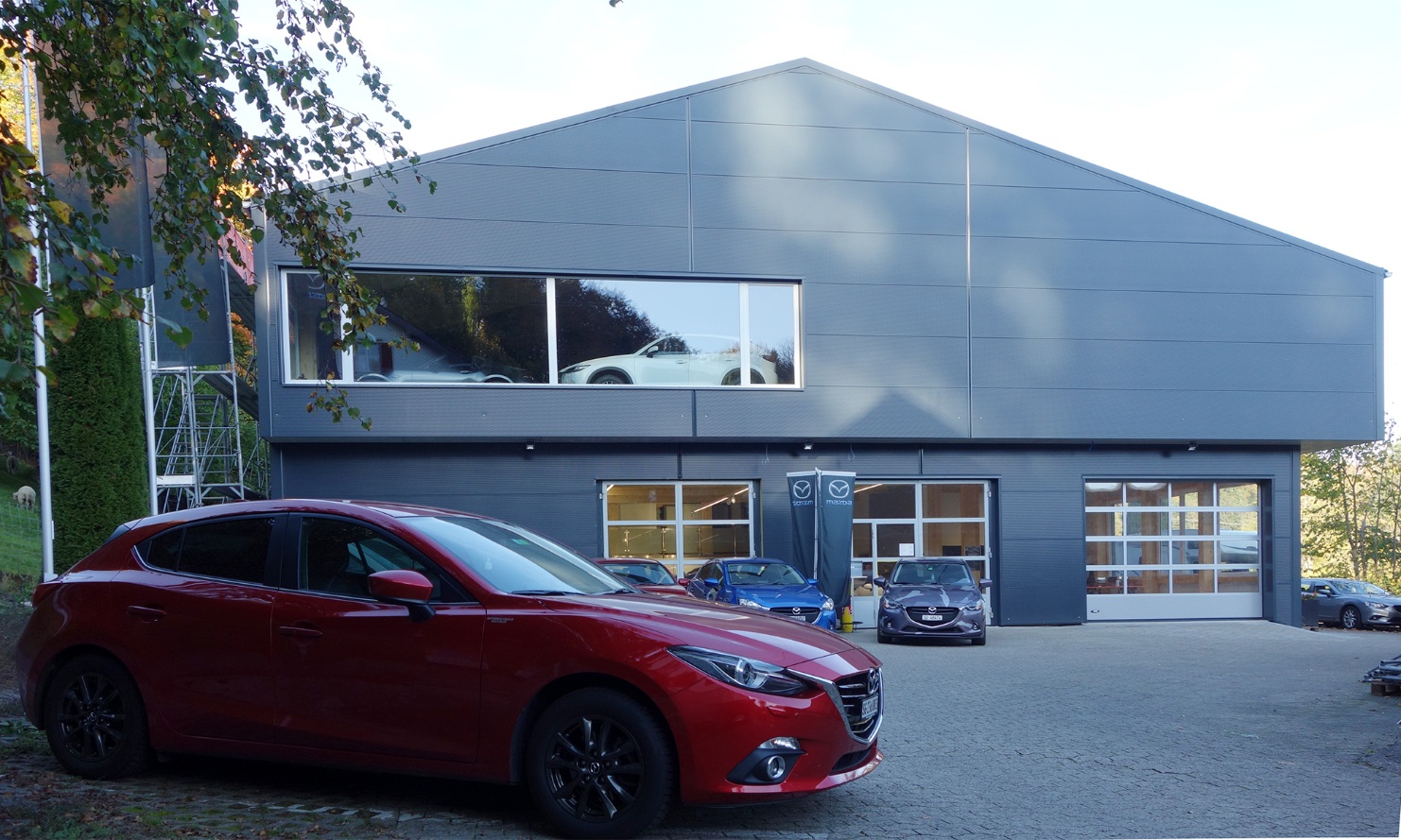 Vue générale du garage Mazda avec une voiture garée devant 