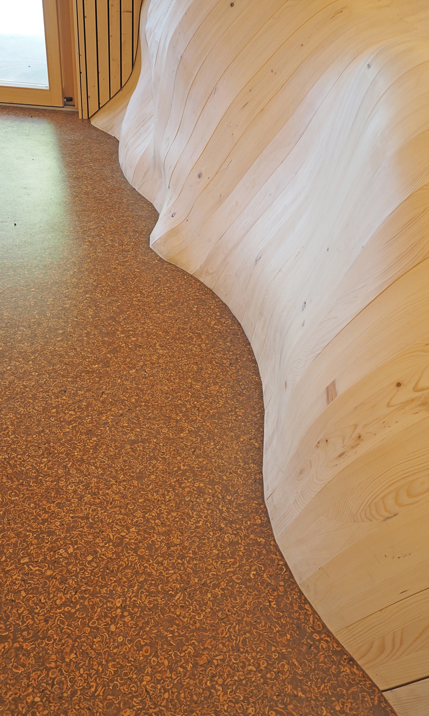 Seitenwände aus vielen einzigartig geformten Holzbauteilen und Fussboden, dessen Material Nussschalen enthält.
