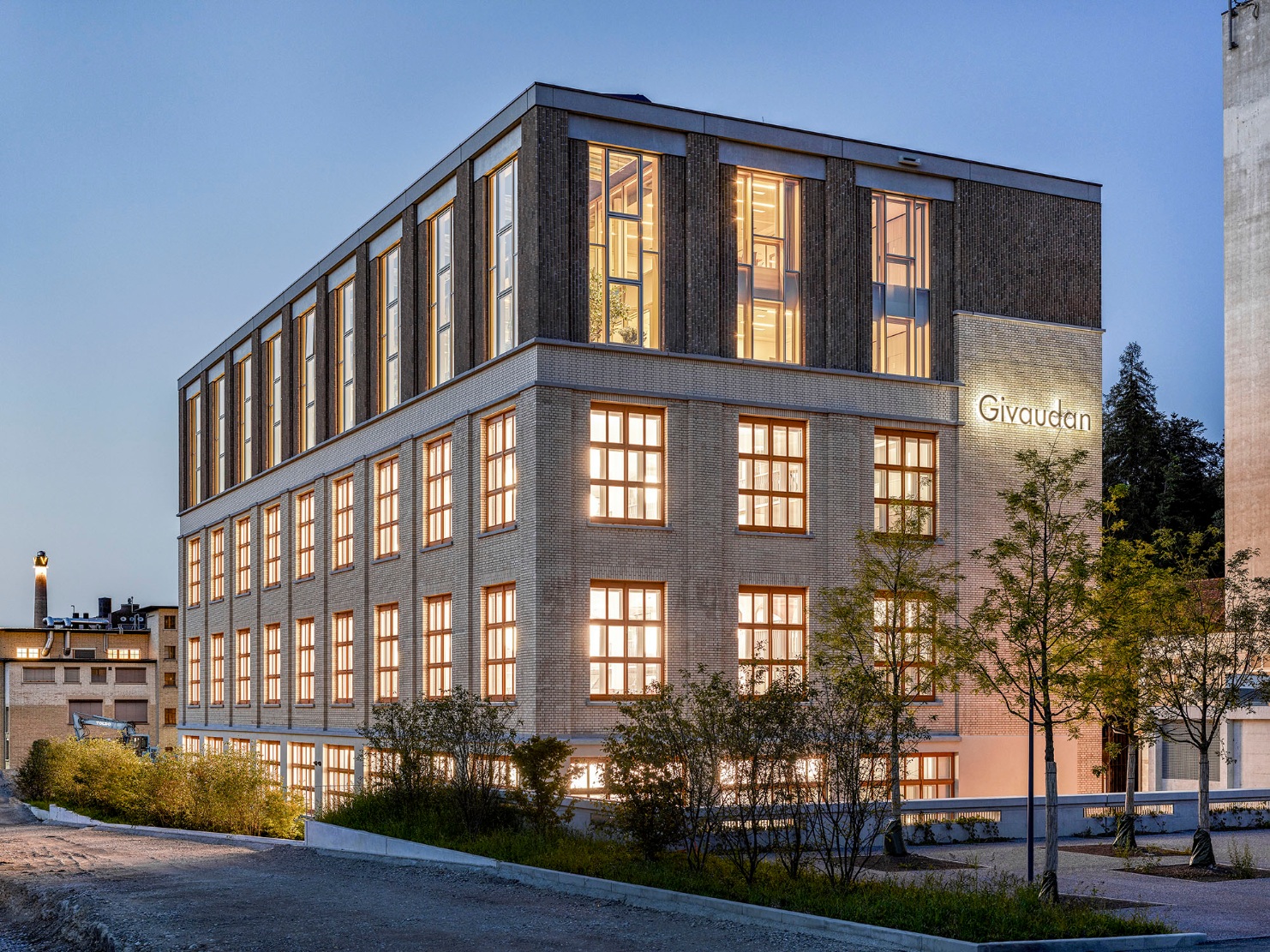 Vue extérieure de l’immeuble de bureaux de Givaudan, récemment transformé, avec des fenêtres très éclairées.