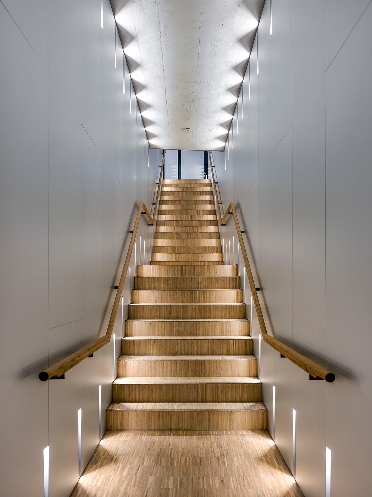 Parquet-clad stairs lead to the upper floor and are visually impressive in how they contrast with the white walls and ceiling.