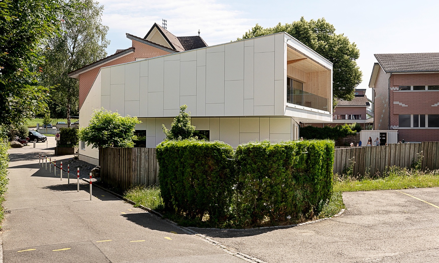 Side view of the converted kindergarten in Wittenbach. The cube-shaped projecting balcony on the top floor is clearly visible.