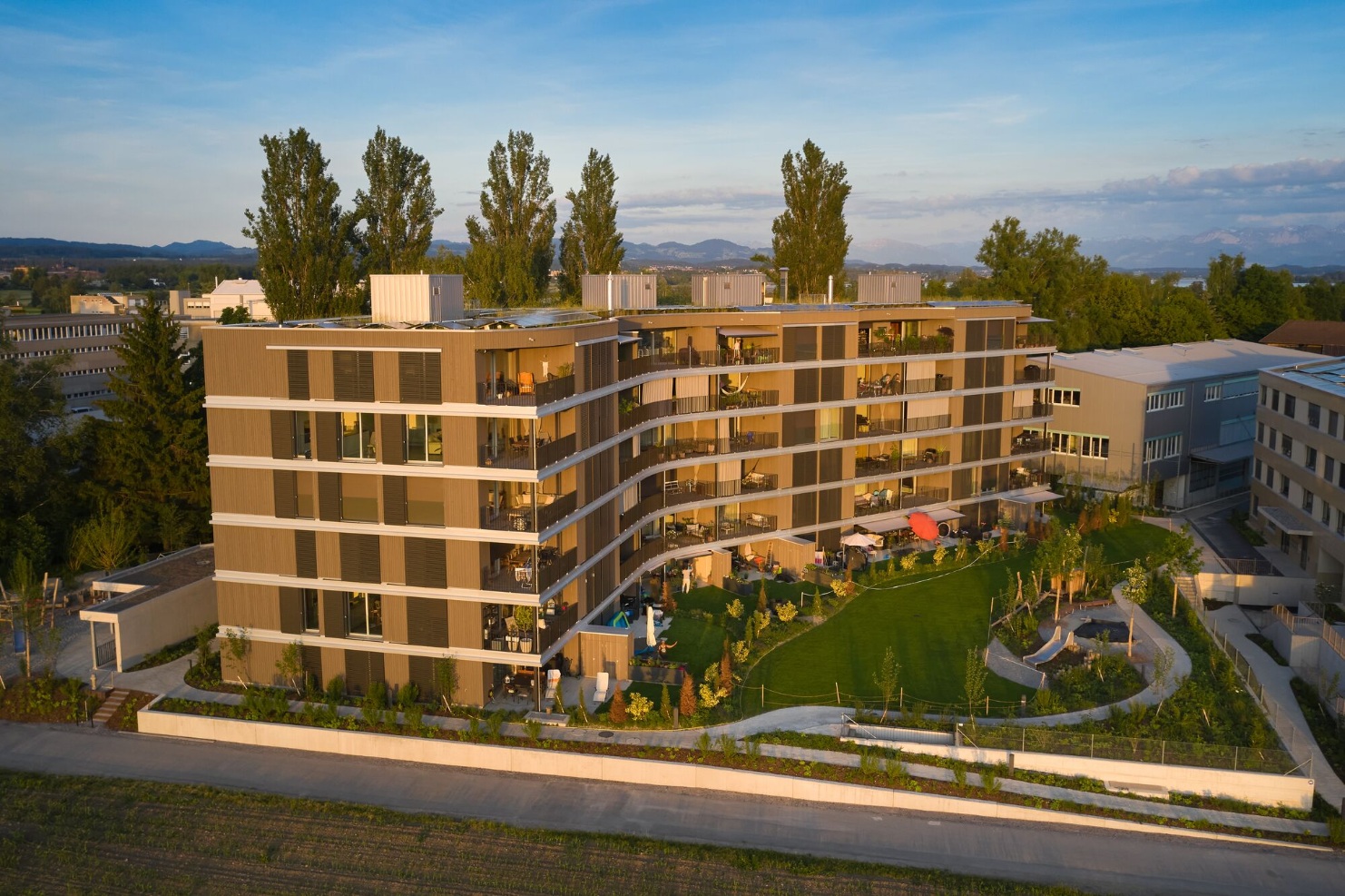 Panoramic view of the six-storey Sunnehof building from the side. The curved shape of the building and the many wooden elements are striking.