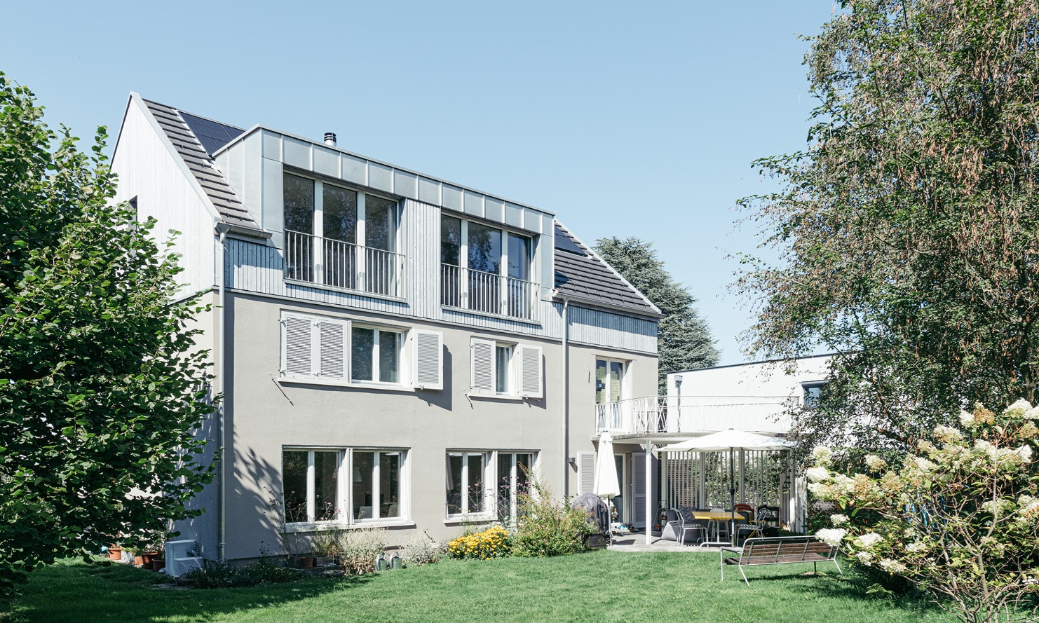 Overall view of the extended detached house with a garden