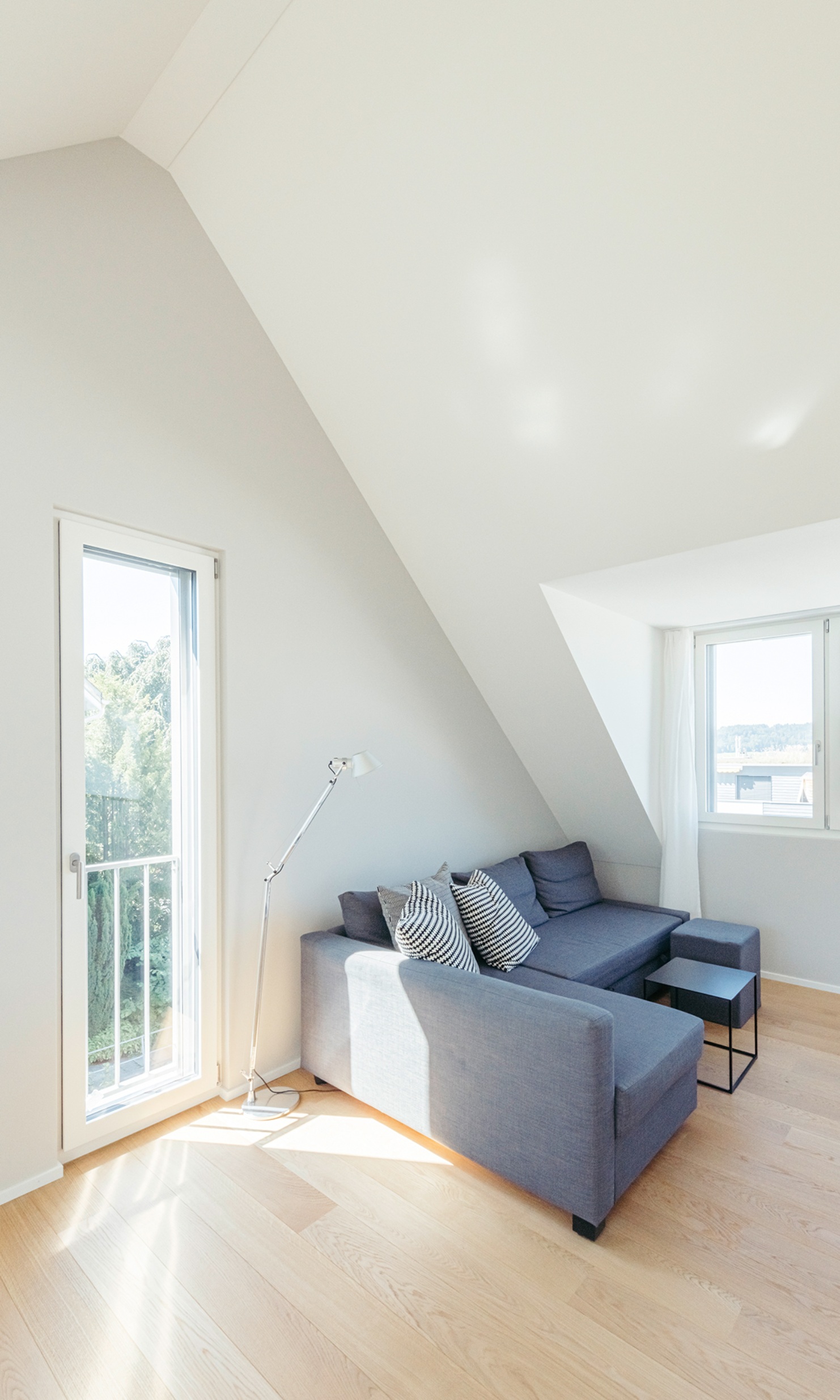 Seating area featuring a grey sofa in the bright living area with parquet flooring in the added storey of the detached house