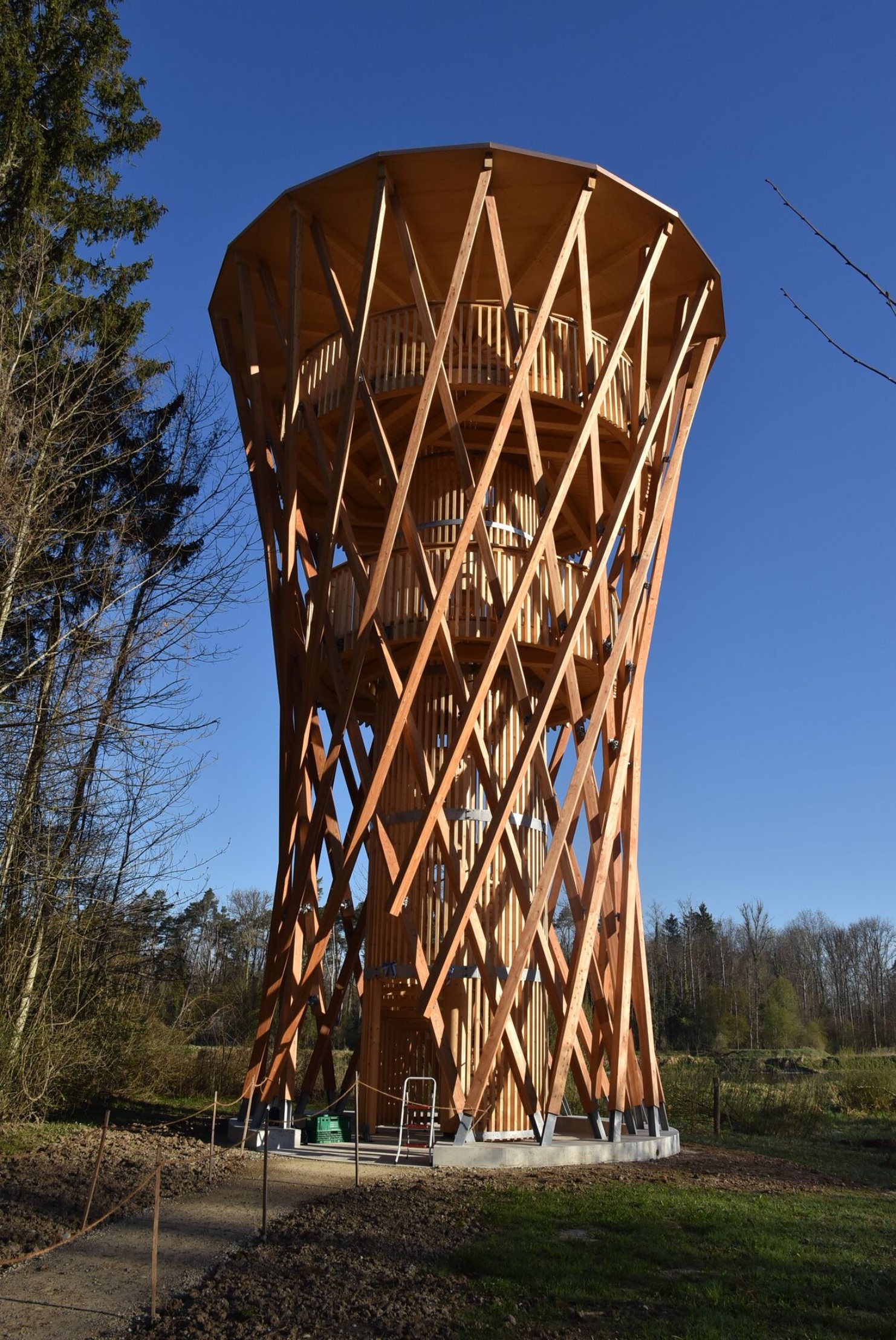 Holzbeobachtungsturm von Blumer Lehmann im Thurauen-Gebiet mit markanter, geschwungene Tragstruktur bei klarem Himmel