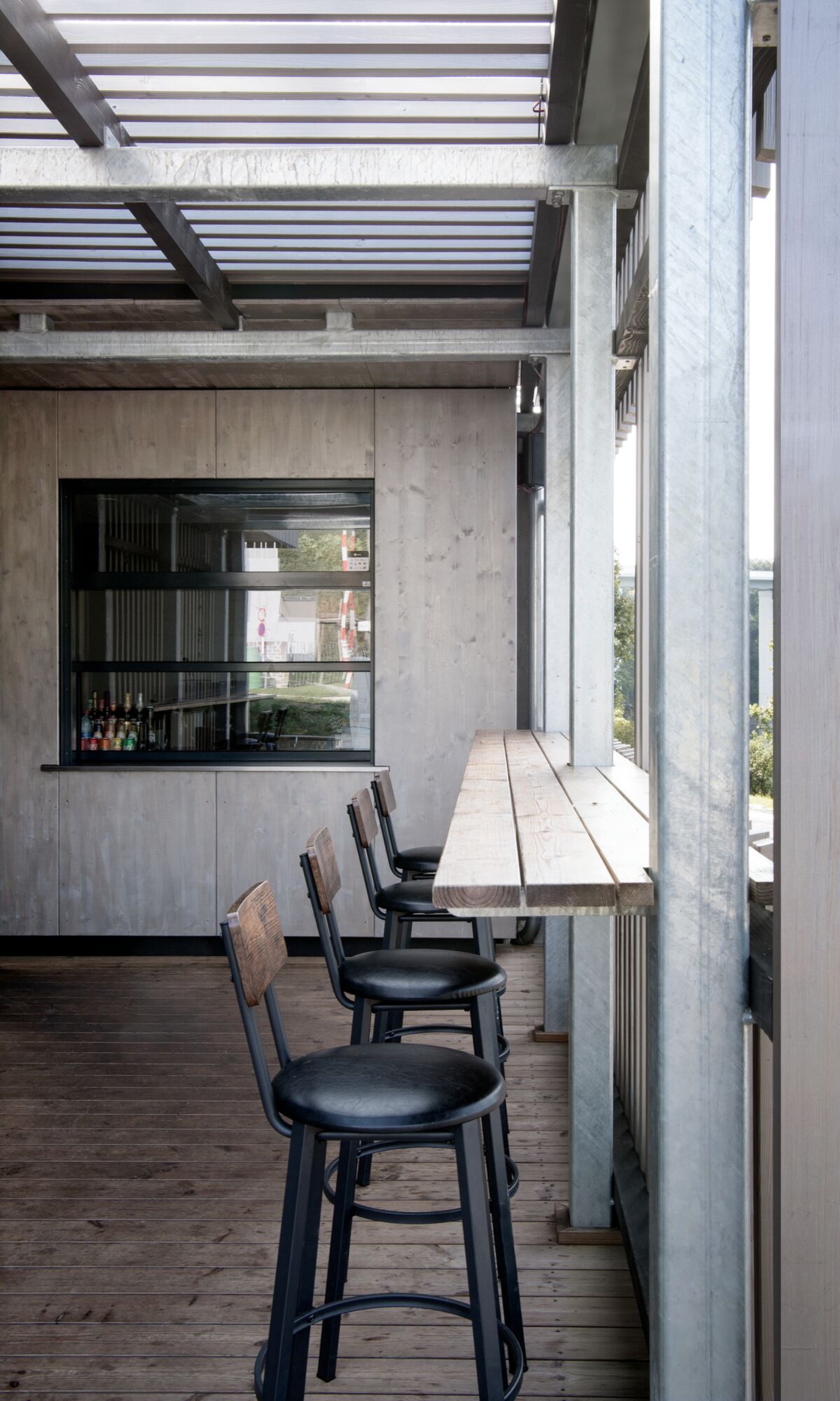 Offen gestaltete Holzterrasse mit Kiosk und Hochtisch
