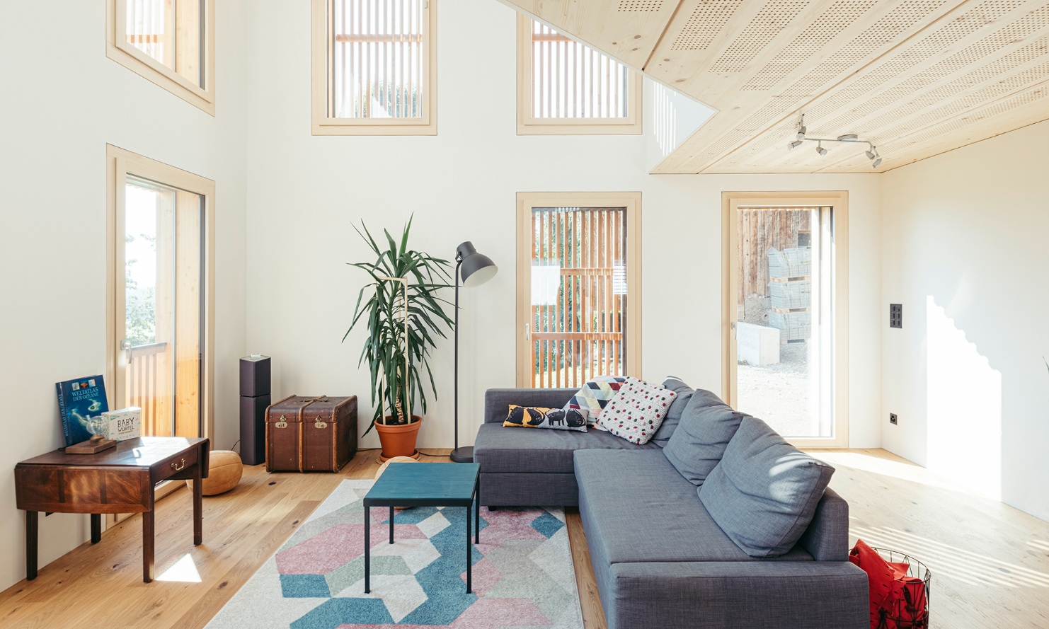 Salon de grande hauteur avec de nombreuses fenêtres et un plafond et un plancher en bois