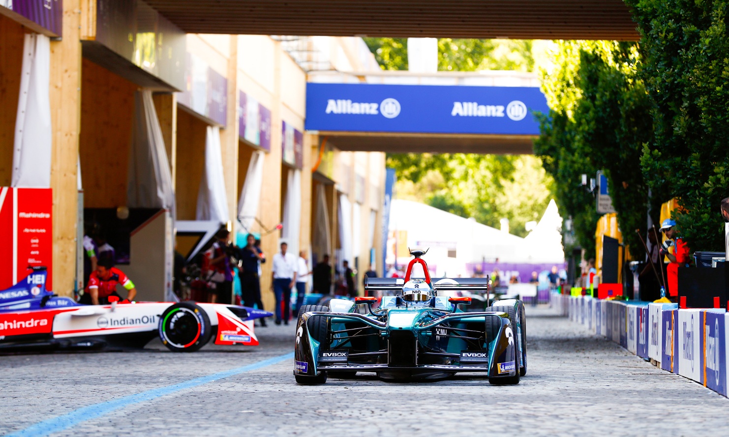 Formel-E Fahrzeug in der Durchfahrt in der Boxengasse. Im Hintergrund hängt eine blaue Werbtafel.