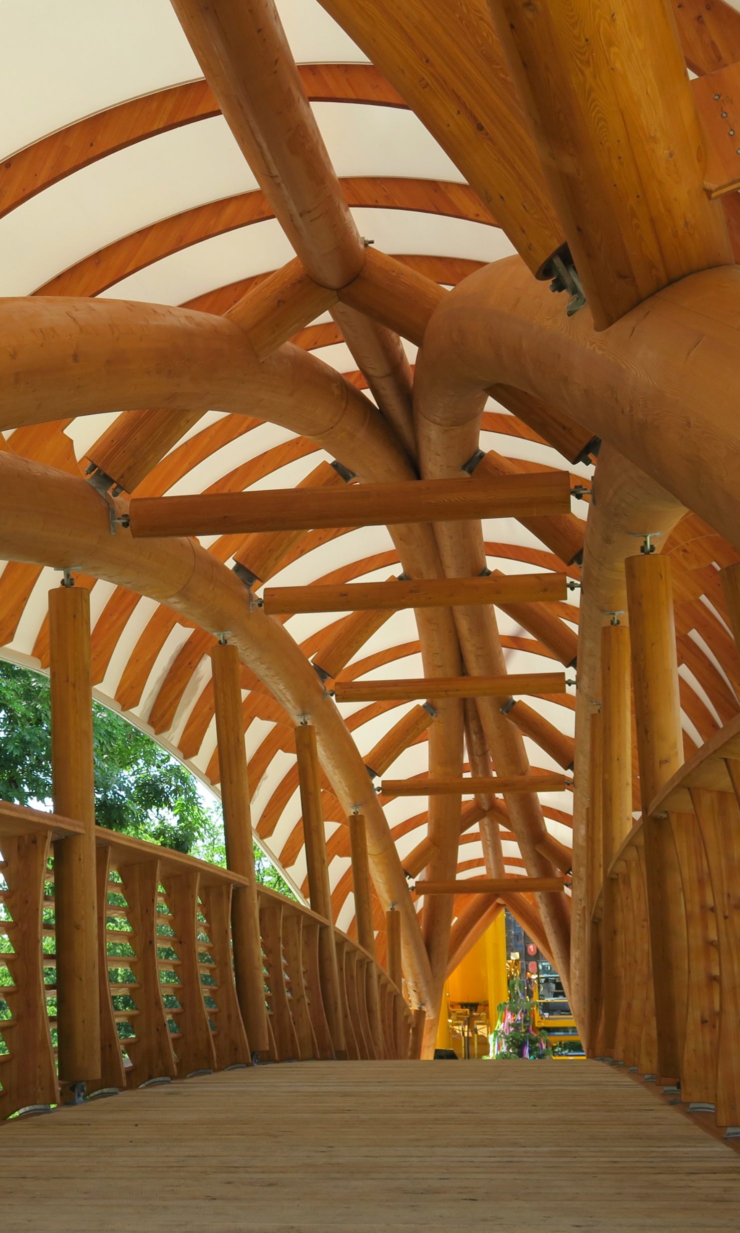 The Aubrugg timber art bridge viewed from the inside. View of curved solid wooden structures and high wooden railings.