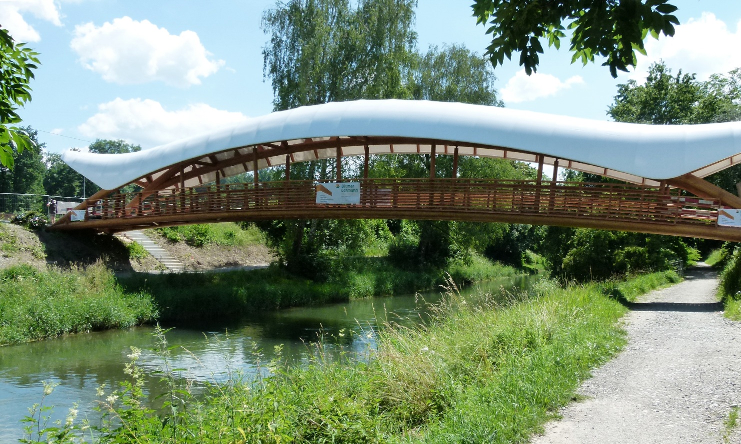Gesamtansicht der Holzkunstbrücke Aubrugg mit einer weiss-geschwungener Überdachung bei schönem Wetter