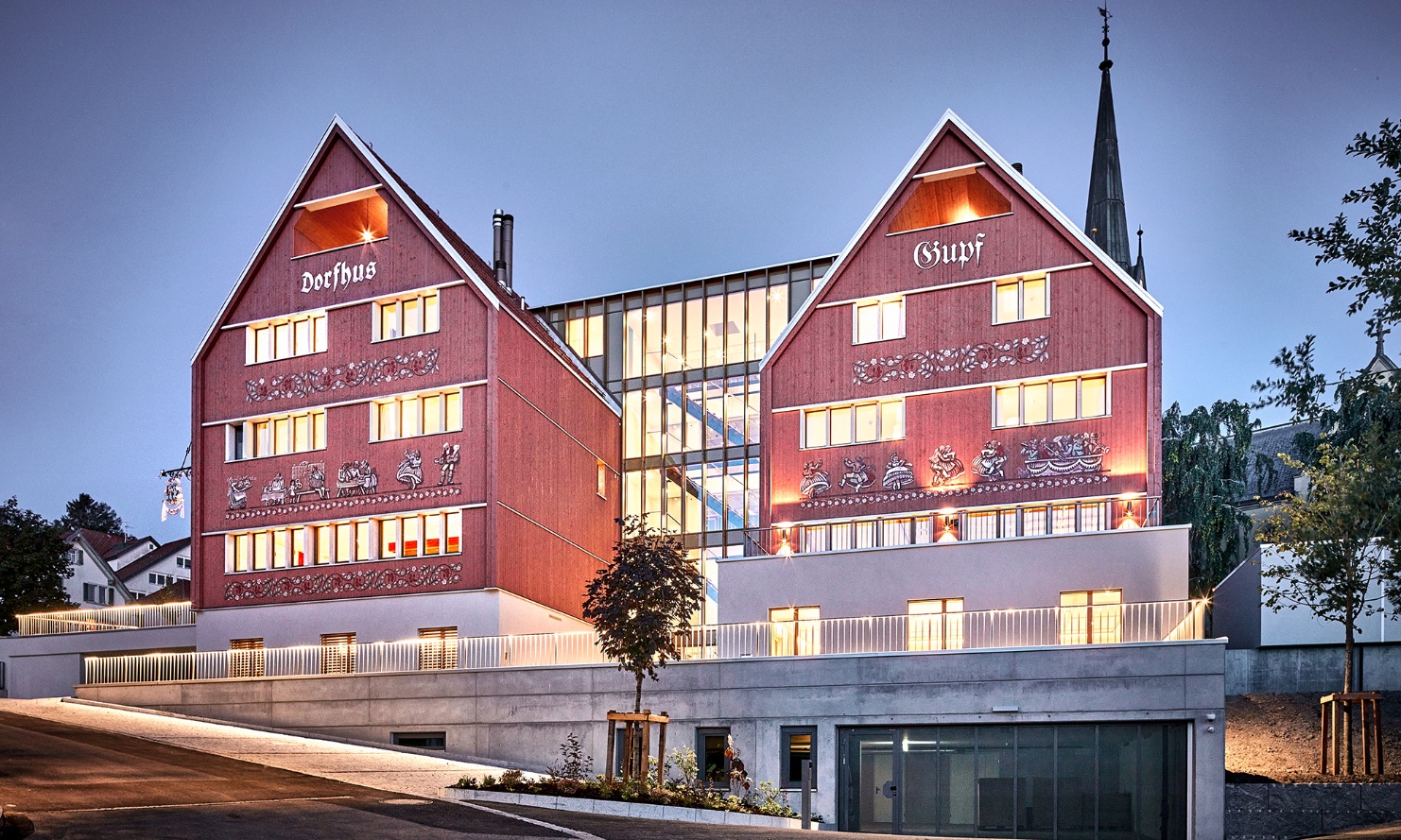 Hôtel Restaurant Dorfhus Gupf avec des fenêtres éclairées par la lumière du soir