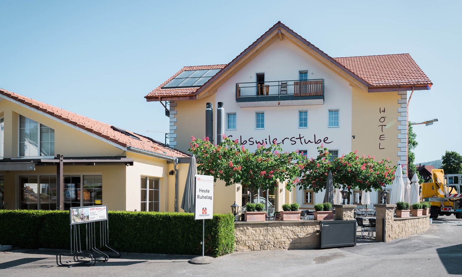 Gesamtansicht der Südfassade des neugebauten Hotels Gibswilerstube; mit Gartenrestaurant im Vordergrund.<br/><br/>