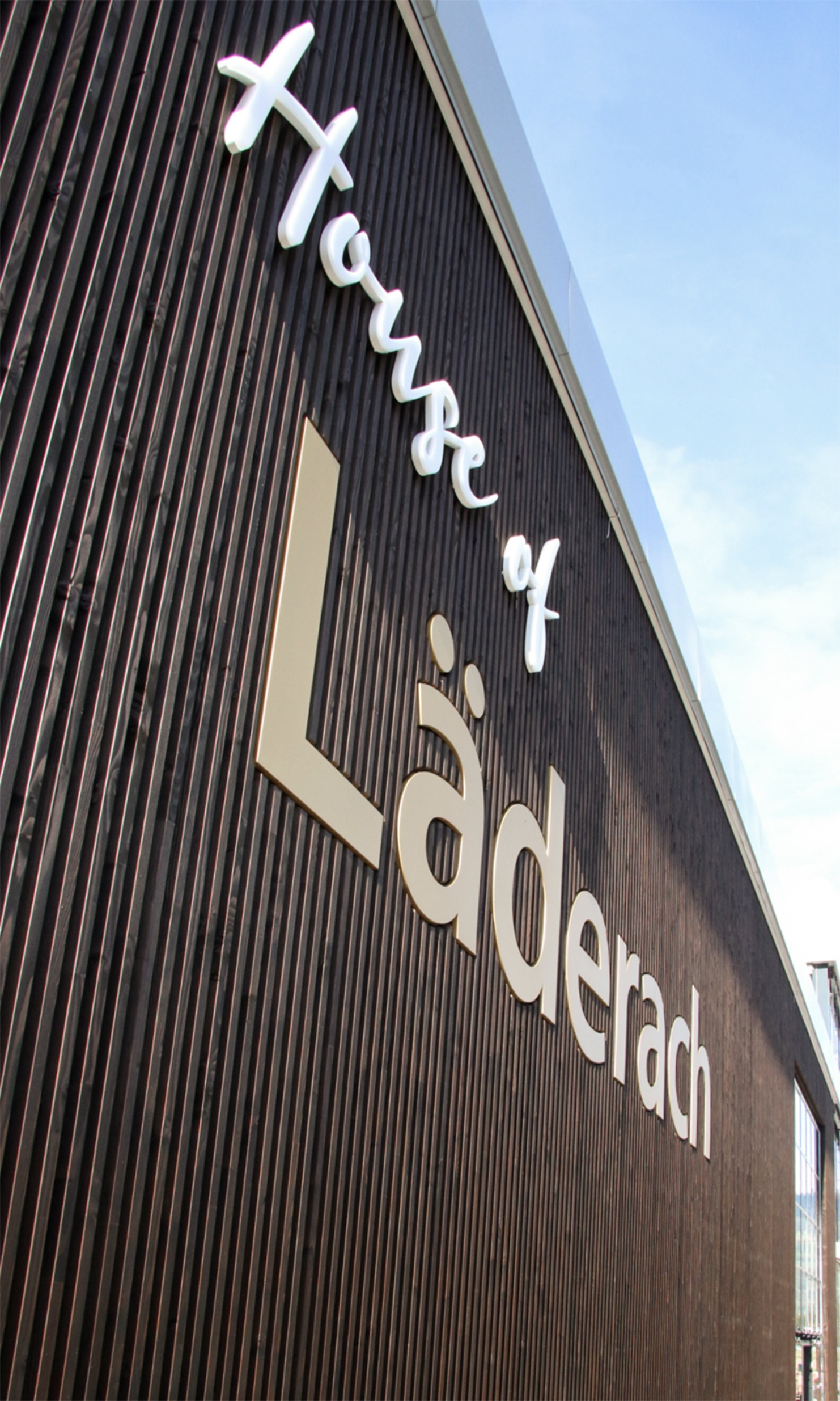 Gebäudefassade aus Douglasienholz mit Schriftzug und Logo