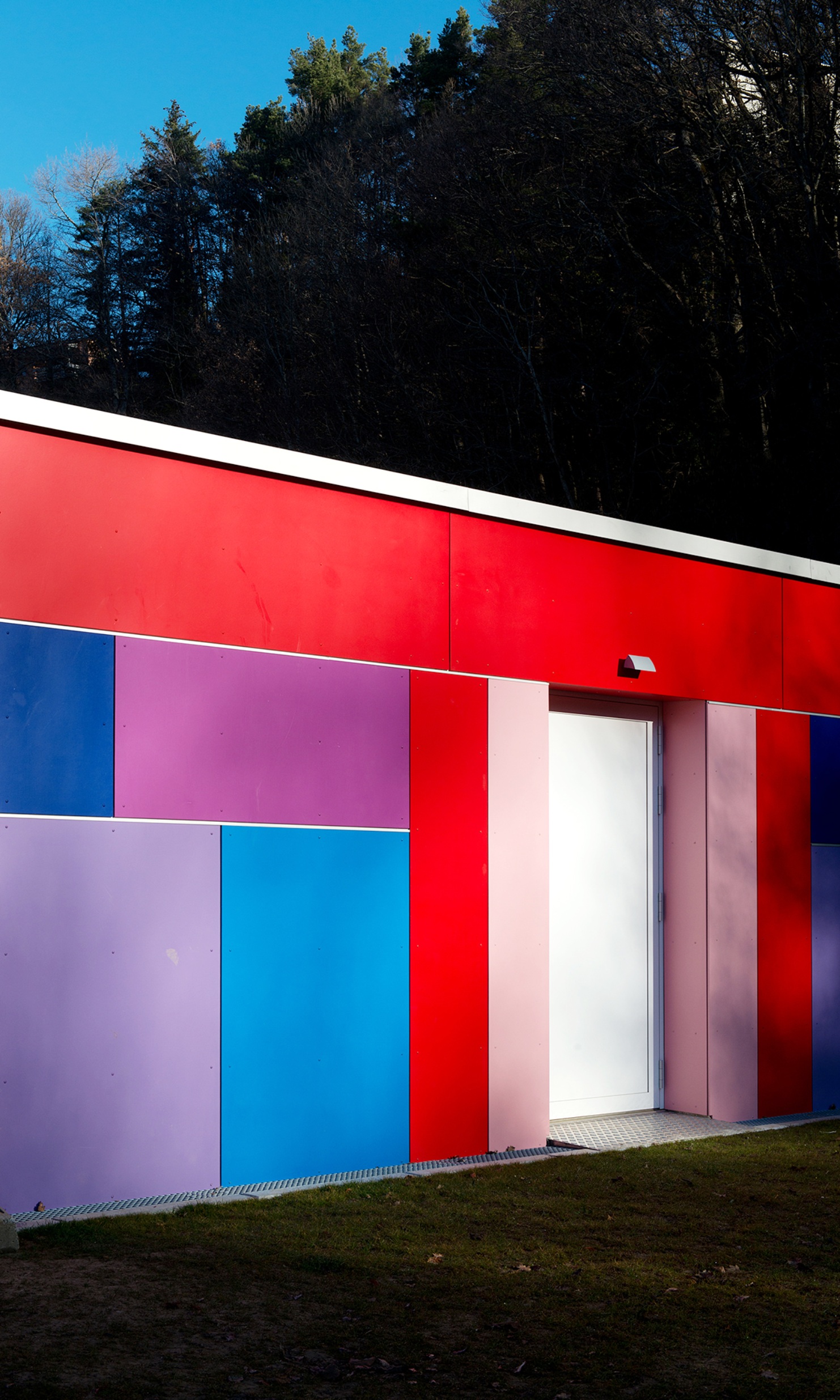 The photograph shows the colourful facade of the modular kindergarten construction