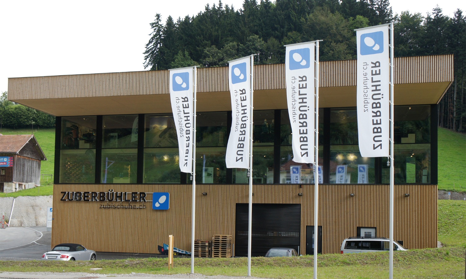 External view of the Zuberbühler industrial building in Herisau with flags in the foreground.