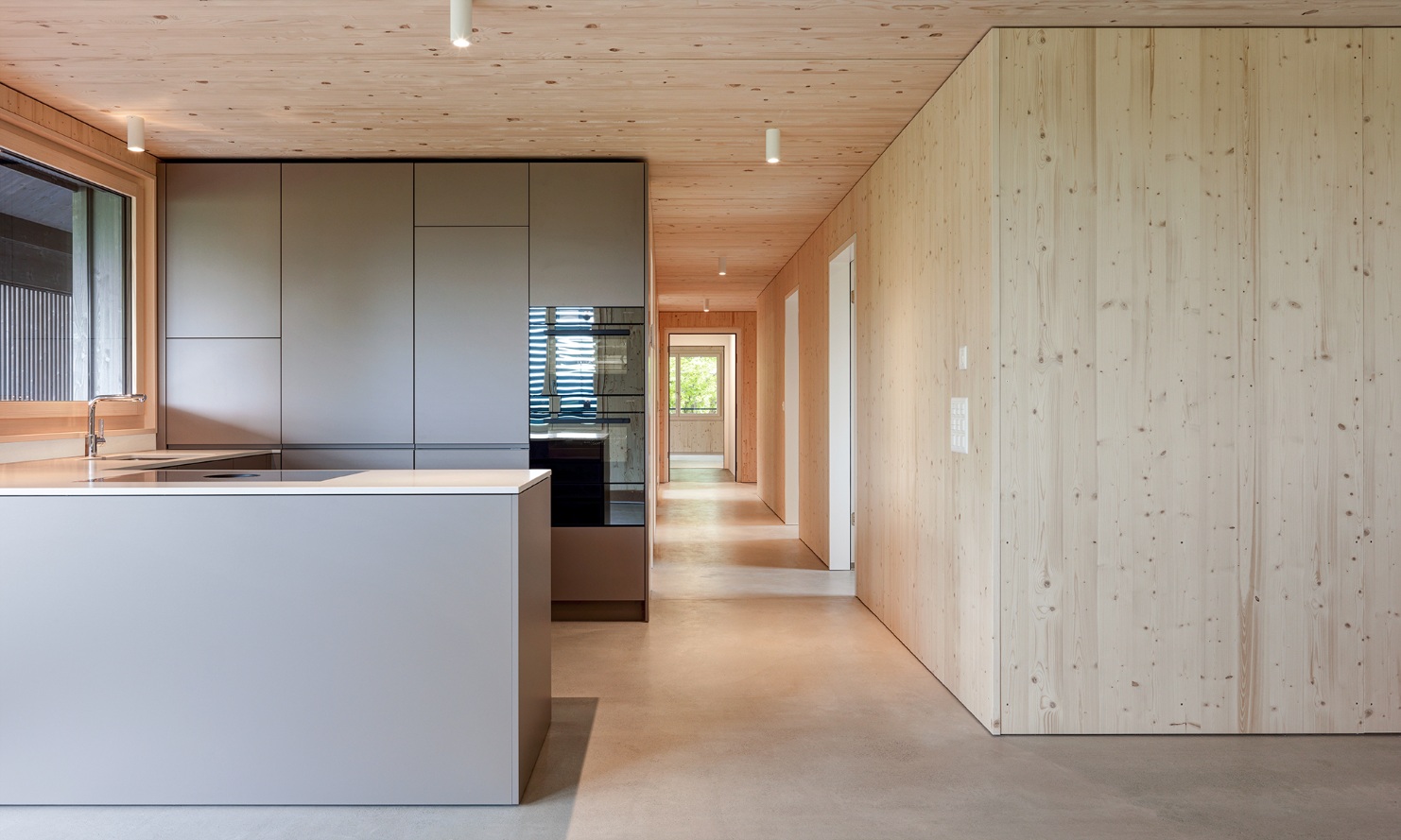 Modern open kitchen in grey, contrasting with the wooden walls, ceiling and floors