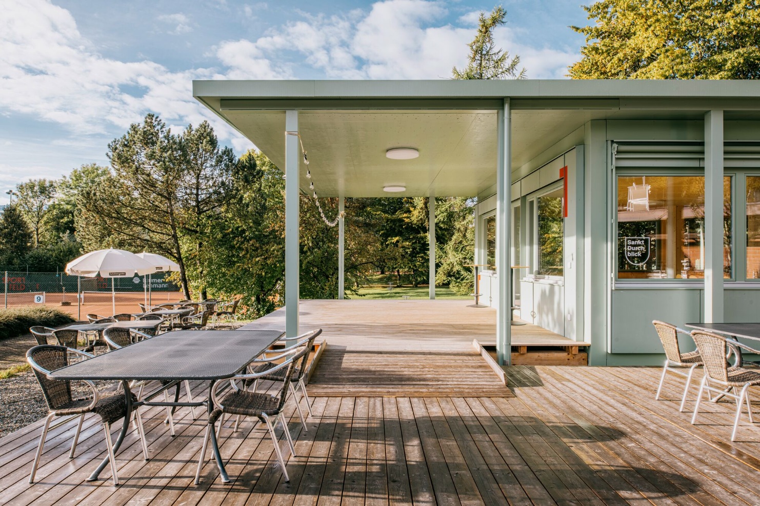Hellgrüner Sportfeldpavillon mit Terrasse und Sitzmöbeln