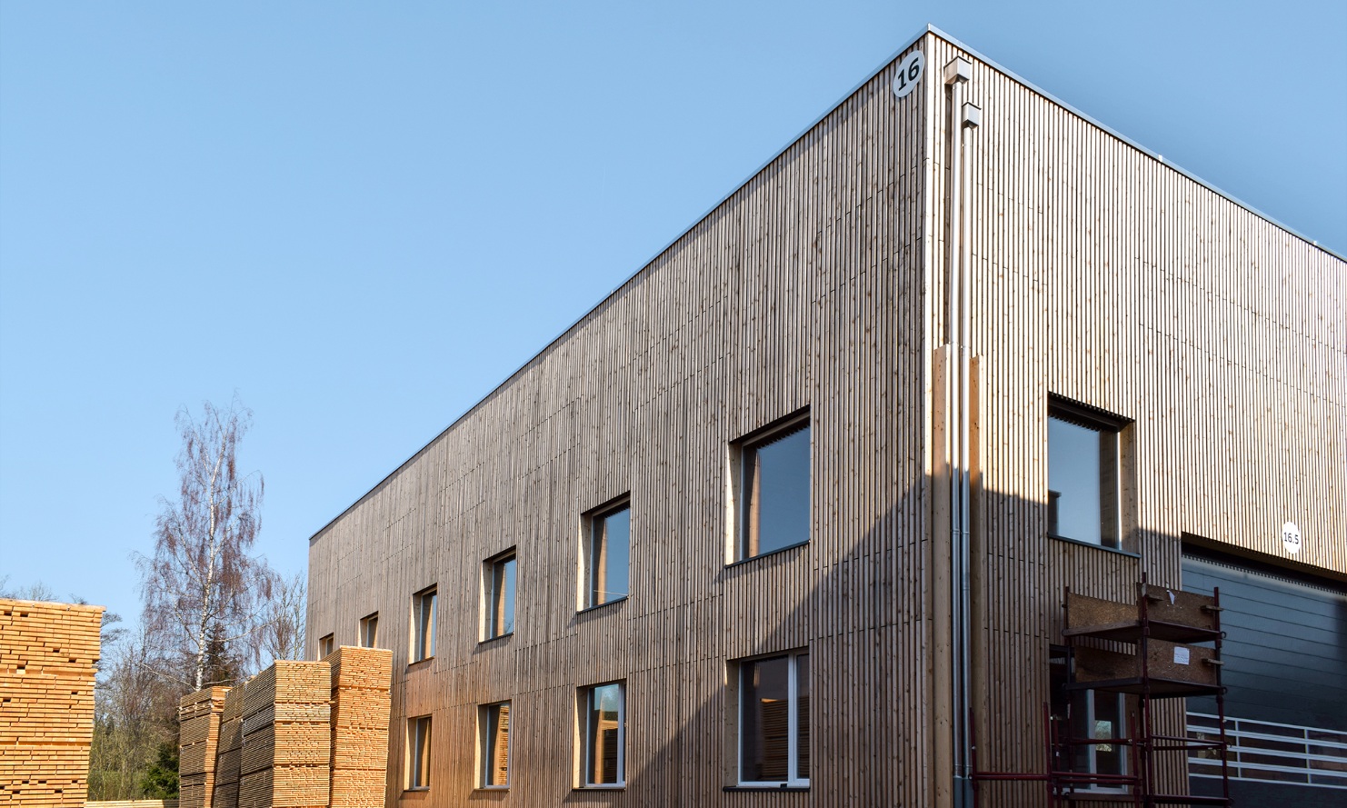 Blick auf die neu erstellte Halle 16 von aussen mit davor gelagerten Holzstapeln