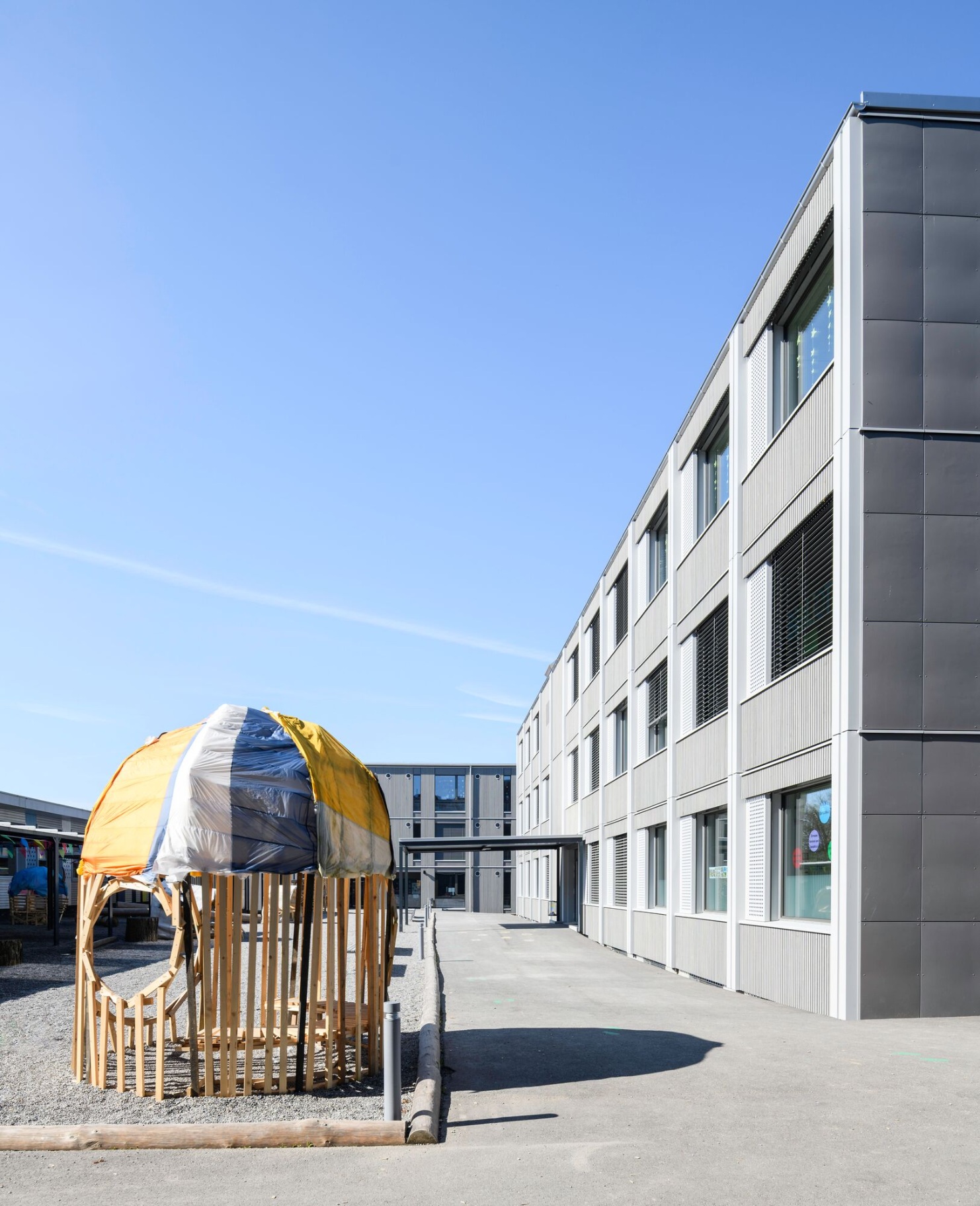 Wooden play structure in the courtyard of the modular Herti school