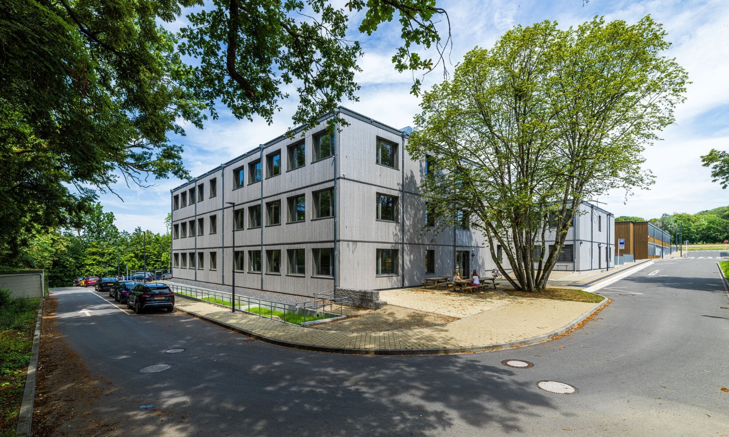 Graue Fassade des Schulmodulbaus mit vertikalen Holzleisten