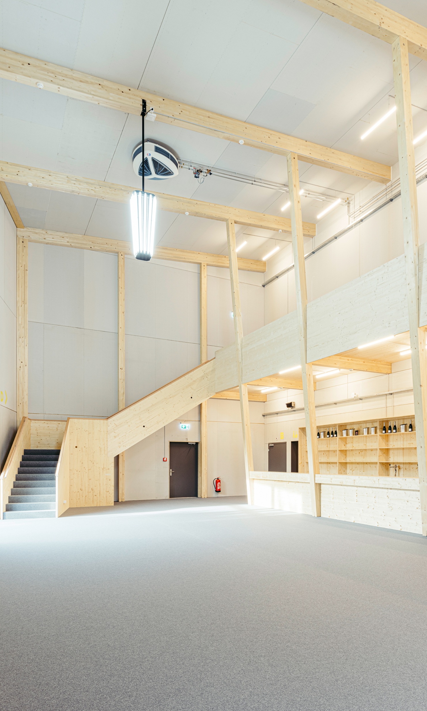 Heller Eingangsbereich mit viel sichtbarem Holz im Theaterprovisorium St. Gallen, mit Foyer, Treppe und Bar. 