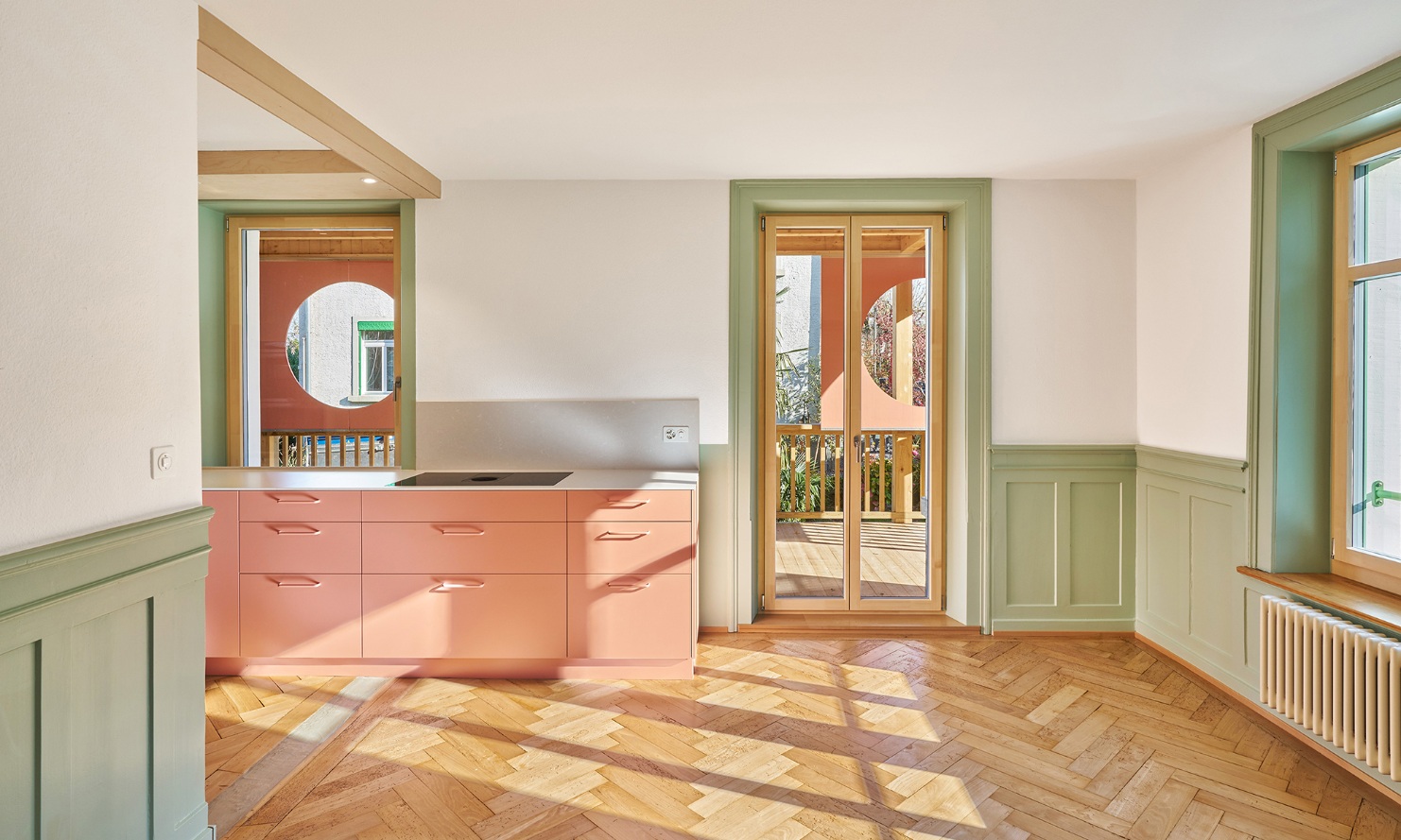 Kitchen in an accenting colour with wooden floor and green interior features