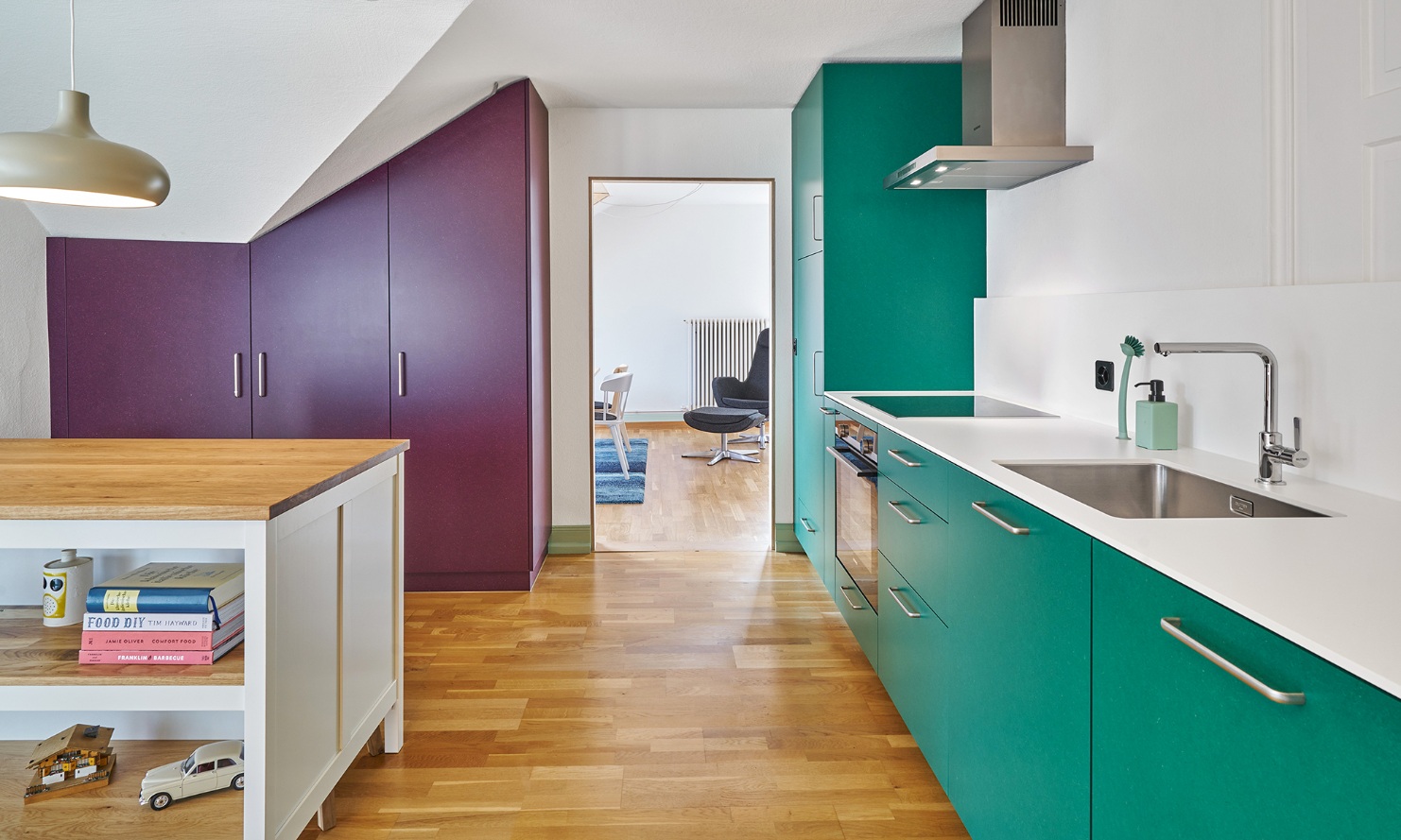 Fitted kitchen with cupboard doors in an accenting colour and wooden floor