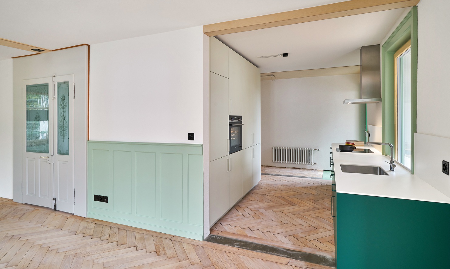 Open-plan kitchen and entrance area with green accenting features