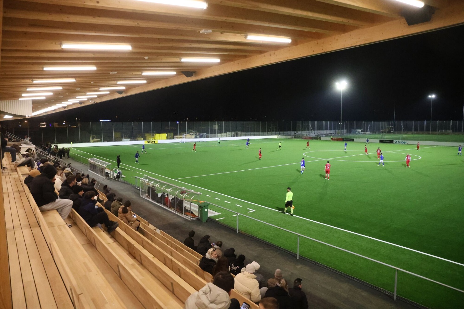 Zuschauer auf der neuen Holztribüne bei einem nächtlichen Fussballspiel im Stadion Gossau