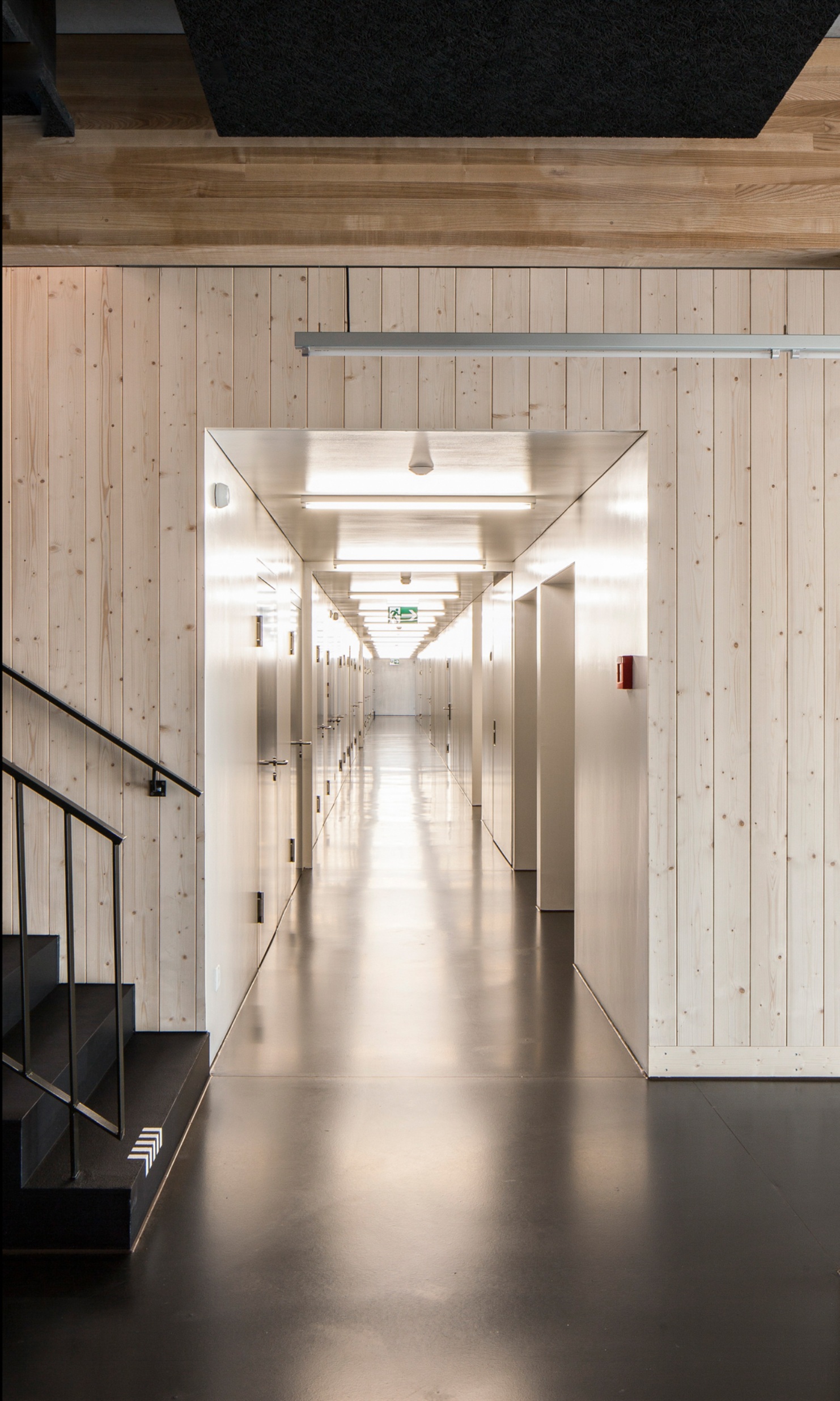 La prise de vue montre un large couloir avec escalier éclairé dans la salle de sport de Sargans