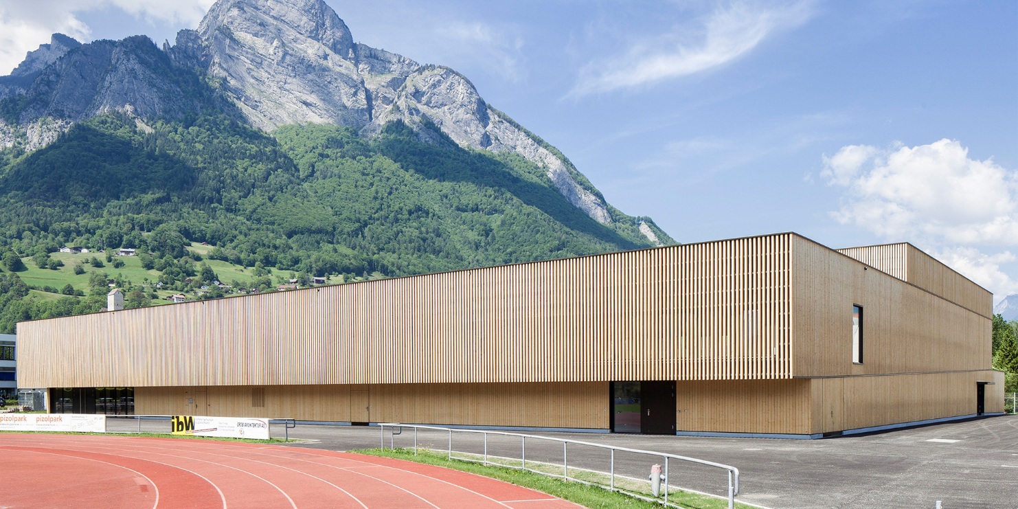 Salle de sport du RSA Sargans avec piste de tartan au premier plan et massif montagneux en arrière-plan.